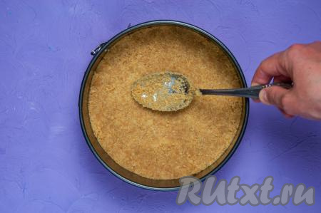 В разъёмную форму (у меня форма диаметром 18 сантиметров) равномерно выложите смесь печенья с маслом, утрамбуйте с помощью ложки. Поставьте форму с основой для торта в морозилку на 20 минут.