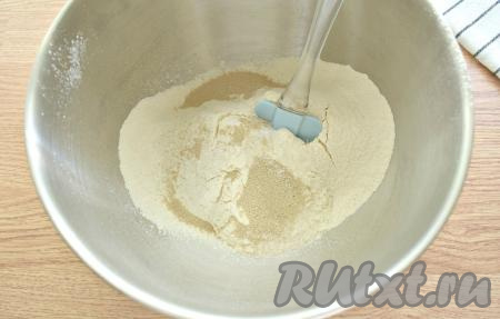 Прежде всего замесим дрожжевое тесто, для этого просеиваем в объёмную миску муку, затем всыпаем соль и сахар, добавляем сухие дрожжи, очень хорошо перемешиваем содержимое миски, делая в центре углубление.