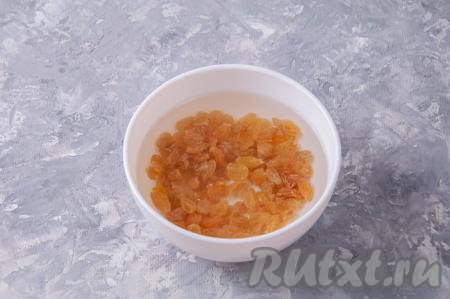 Изюм промойте, выложите в небольшую ёмкость, залейте его кипятком и оставьте для набухания минут на 10. Затем лишнюю воду слейте, а изюм обсушите на полотенце.