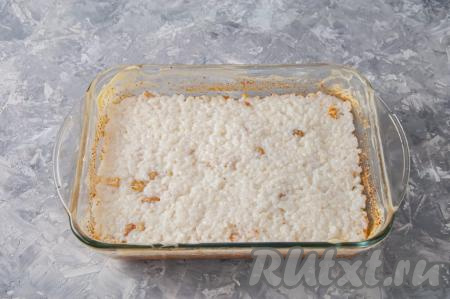 Выложите рис, смешанный с изюмом, в форму для запекания, разровняйте поверхность ложкой.