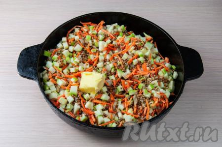 Затем к гречке с луком добавьте натёртую на крупной тёрке морковку, нарезанный на небольшие кубики кабачок и сливочное масло, посолите, поперчите по вкусу и перемешайте.