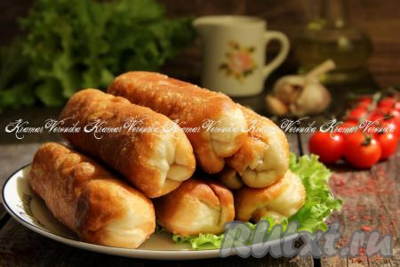 Готовые жареные сосиски в тесте переложить со сковороды на тарелку. Постепенно пожарить все заготовки. Подать вкусные, аппетитные сосиски в воздушном дрожжевом тесте к столу.