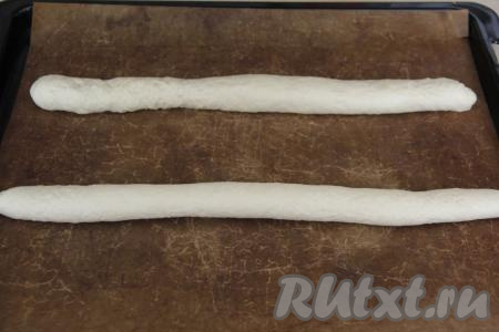 Выложить заготовки багетов на противень, застеленный ковриком для выпечки (или пергаментом). Оставить багеты для расстойки на 30 минут, накрыв полотенцем.