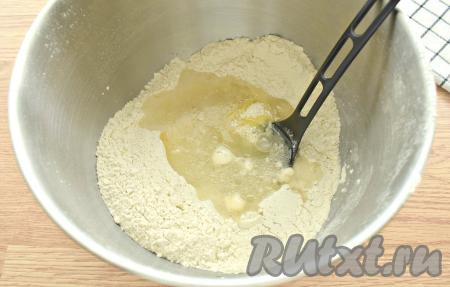 В центр получившейся смеси разбиваем яйцо, вливаем тёплую кипячёную воду (температура воды должна быть не выше 40 градусов) и растительное масло.