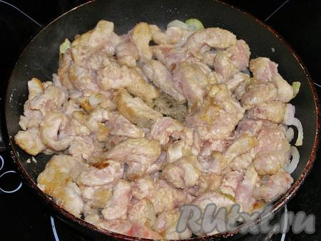 Кладём в сковородку с луком кусочки свинины, обжариваем, помешивая, 5-6 минут (до подрумянивания мяса со всех сторон).