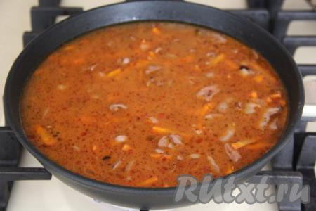 Влить в сковороду 400 миллилитров воды комнатной температуры. После этого перемешать, довести воду до кипения и сразу убавить до минимума огонь. Добавить зубчики чеснока, затем сразу накрыть сковороду крышкой. Готовить плов с куриными сердечками до полного испарения жидкости (примерно, 20 минут).