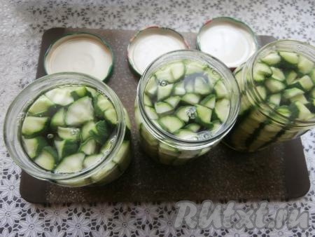 Залить огурцы крутым кипятком, прикрыть банки заранее прокипячёнными крышками и оставить на 10 минут.