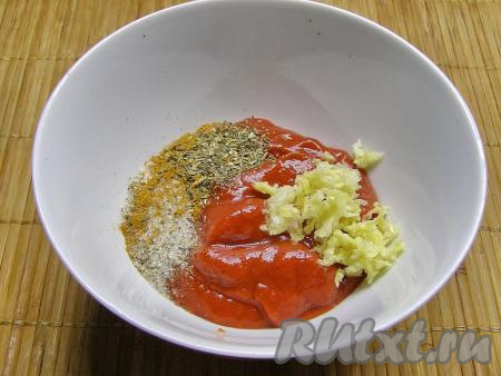 Для приготовления томатного соуса перекладываем томатную пасту в глубокую тарелку, добавляем в неё измельчённый через пресс чеснок, а также сушёную зелень, перчим и солим по вкусу. Затем добавляем холодную воду и перемешиваем до однородного состояния. Вместо томатной пасты можно использовать измельчённые блендером или мясорубкой свежие помидоры, помидоры в собственном соку, томатный соус или кетчуп, но в этом случае воды нужно будет добавить меньше. Ориентируйтесь на консистенцию соуса - он не должен быть очень жидким, но в то же время и не очень густым.