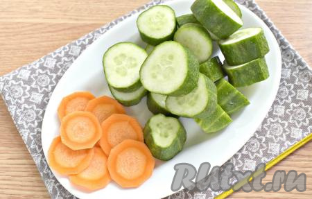 Заранее банку объёмом 0,5 литра стерилизуем удобным способом (я стерилизовала над паром), а крышку с момента закипания воды стерилизуем в течение 3 минут. Огурцы моем, затем с двух сторон у каждого огурчика отрезаем кончики. Нарезаем огурцы на кружочки толщиной около 2 сантиметров. Очищаем морковку и нарезаем её на тонкие кружочки.