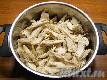 С остывшей курицы снимаем кожицу, а затем отделяем куриное мясо от костей, перекладываем в миску. Крупные куски мяса можно нарезать помельче.