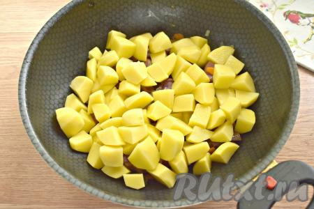 Очищенную картошку нарезаем на средние кубики, добавляем на сковороду с овощами и копчёными рёбрышками.