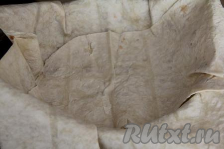 Выложить два листа лаваша, застилая дно и бока сковороды, края лаваша должны свисать с краёв сковороды.&nbsp;