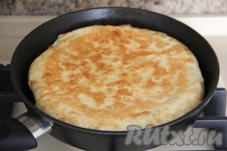 Накрыть сковороду крышкой и поставить на огонь. Выпекать пирог из лаваша с сыром на минимальном огне минут 10-15, затем перевернуть его на другую сторону (можно сначала перевернуть на плоскую тарелку, а затем вернуть пирог на сковороду) и выпекать ещё минут 10 (до золотистости лаваша).