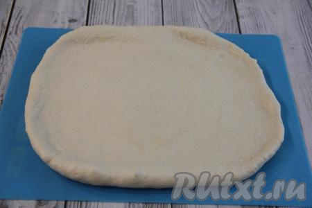 Переложить поднявшееся тесто на силиконовый коврик (или на стол, присыпанный мукой) и обмять. Раскатать тесто в не тонкий прямоугольный пласт.