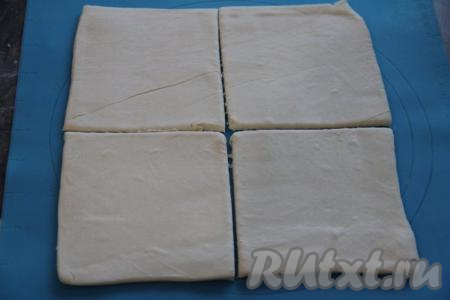 Пласт слоёного теста слегка раскатать на силиконовом коврике (или на припылённой мукой поверхности) и разрезать на 4 квадрата.