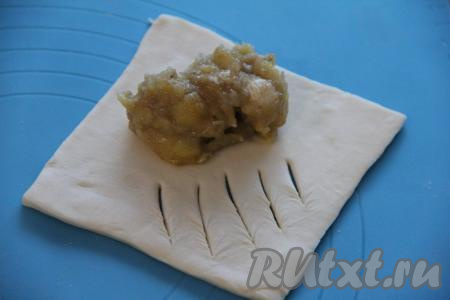 Выложить 1/4 часть начинки ближе к одному из углов, немного отступив от краёв. Сделать разрезы на противоположной стороне теста, как на фото.