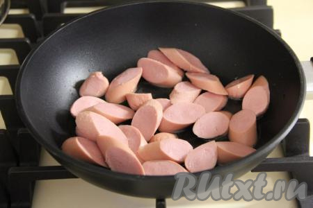 В сковороду влить немного масла и выложить сосиски, нарезанные на средние кружочки (тонко нарезать не нужно).