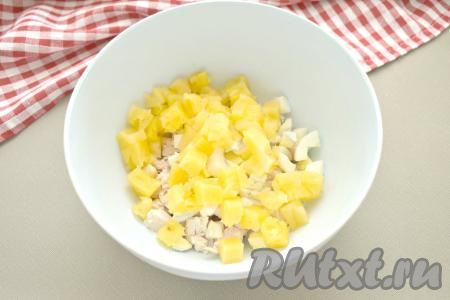 Для этого салата я использовала консервированные кольца ананаса. Ананасы тоже нарезаем на средние кубики и перекладываем их в миску с курицей и яйцами.
