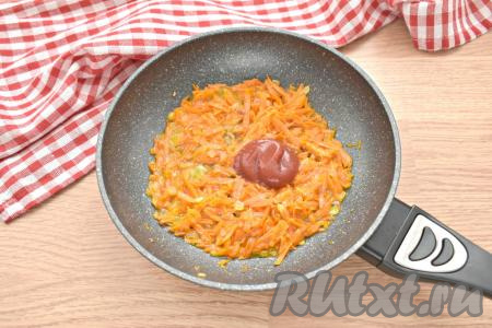 К луку и морковке добавляем томатную пасту, вливаем 2-3 столовых ложки бульона из кастрюли, перемешиваем и тушим овощи 3-4 минуты.