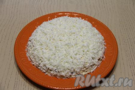 Затем белки натереть на мелкой терке и выложить ровным слоем, покрывая салат и сверху, и с боков. Поставить пропитаться в холодильник минут на 30.