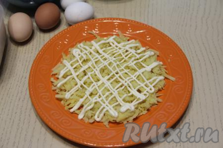 Очистить остывший картофель, натереть на крупной тёрке и выложить на плоскую тарелку, посолить по вкусу, разровнять и нанести сеточку из майонеза.