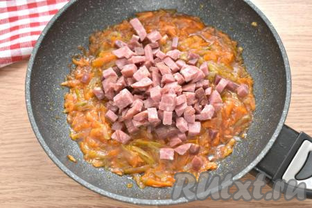 Затем добавляем в сковороду колбасу, нарезанную на маленькие кубики, перемешиваем, томим 3-4 минуты.