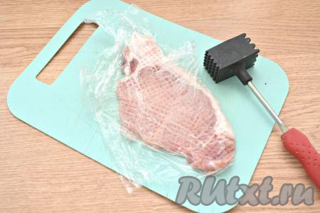 Получившиеся стейки из свинины накрываем пищевой плёнкой и отбиваем молоточком для мяса.