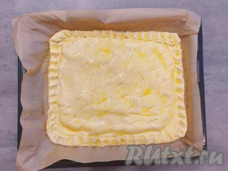 Поверхность слоёного пирога смазываем яичным желтком и посыпаем сверху кунжутом.