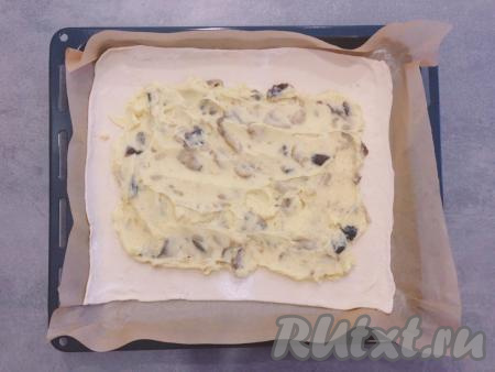 Одну часть теста аккуратно перекладываем на противень, застеленный пергаментной бумагой (ничем бумагу не смазываем). На тесто равномерно выкладываем остывшую картофельно-грибную начинку, немного отступив от краёв теста (как на фото).