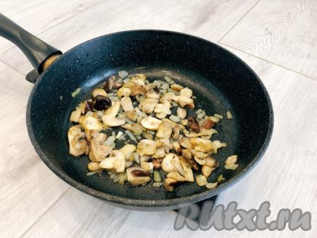 Далее необходимо приготовить грибы. Если вы используете свежие шампиньоны или вешенки, тогда их нужно промыть, обсушить и нарезать на произвольные ломтики. Если готовите со свежими лесными грибами, тогда их нужно перебрать и отварить в течение 25-30 минут с момента закипания грибов, затем слить лишнюю воду. Я взяла замороженные покупные грибы. Лук очищаем, нарезаем достаточно мелко. Замороженные (или отваренные лесные, или подготовленные свежие) грибы и нарезанный лук выкладываем в сковороду, разогретую с растительным маслом, солим, перчим по вкусу, обжариваем на среднем огне 7-10 минут, периодически перемешивая.