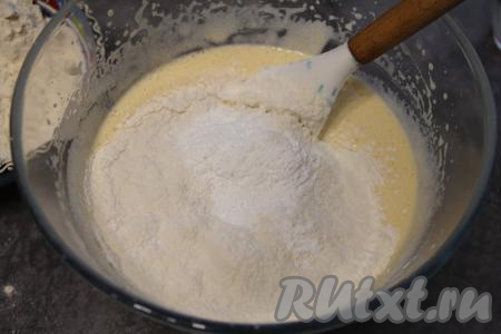 Затем в смесь яиц, кефира и масла добавить разрыхлитель, частями начать всыпать просеянную муку, перемешивая тесто лопаткой.