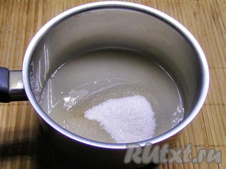 В сотейнике соединяем сахар и 100 миллилитров воды, перемешиваем и ставим на средний огонь.