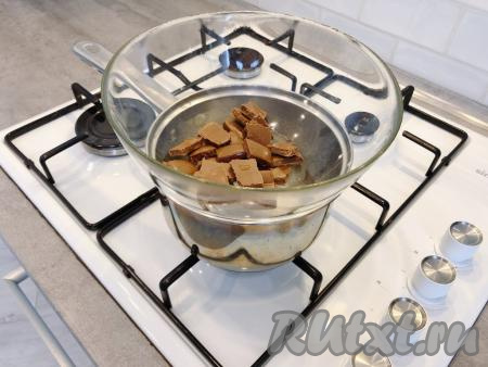 Примерно за 10 минут до того, как придёт время доставать десерт из холодильника, приступаем к приготовлению глазури. Для этого разламываем шоколад на дольки, складываем в чашку, добавляем растительное масло и ставим на водяную баню (для этого в сотейник наливаем немного воды, сверху устанавливаем чашку с дольками шоколада и масла, всю эту конструкцию ставим на средний огонь). 