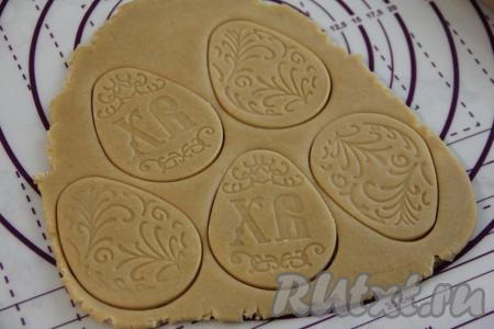 Готовое тесто разделить на несколько частей. Каждую часть теста на присыпанной мукой поверхности раскатать скалкой в пласт толщиной примерно 0,5 сантиметра. Вырезать пряники нужной формы (это можно сделать с помощью формочек для печенья, а если вы готовите тематические пряники, тогда можно взять покупной трафарет нужной формы или заранее вырезать нужный трафарет из бумаги, приложить к раскатанному тесту и вырезать ножом). Я готовила пасхальные пряники, формируя их в виде яиц с помощью покупной формы со штампом, которая выдавливает рисунок.