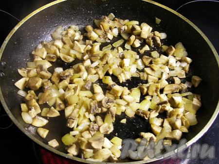 Теперь приготовим курино-грибную начинку. Для этого очищаем лук, ополаскиваем водой и нарезаем на кубики среднего размера. Шампиньоны моем, удаляем с них загрязнения и нарезаем на средние кубики. Можно использовать замороженные шампиньоны (или предварительно отваренные в течение 25-30 минут лесные грибы). Обжариваем лук с грибами на растительном масле, иногда помешивая, на среднем огне минут 10 (до испарения влаги из грибов). Если вы используете замороженные грибы, тогда их не нужно размораживать, но обжаривать их нужно будет минут 20.