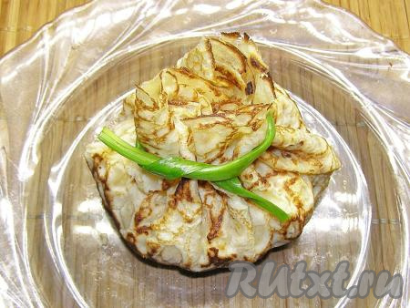 Приподнимаем края блинчика и складываем их вверху, придавая блину форму мешочка. Завязываем мешочек пером зелёного лука. Если вы не хотите делать мешочки, можно просто сложить блин в форме конвертика.