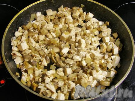 Остывшее куриное мясо нарезаем на небольшие кусочки, перекладываем к грибам, обжаренным с луком, перемешиваем, солим, перчим и тушим на слабом огне под крышкой минут 5, иногда помешивая,  затем снимаем сковородку с огня.