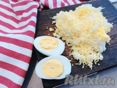 Куриные яйца отвариваем до готовности (в течение 10 минут с момента закипания), затем заливаем их холодной водой, а после остывания очищаем и натираем на мелкой тёрке.