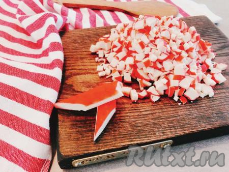 Крабовые палочки заранее размораживаем при комнатной температуре, затем снимаем с них слюду. Нарезаем крабовые палочки на небольшие кубики.