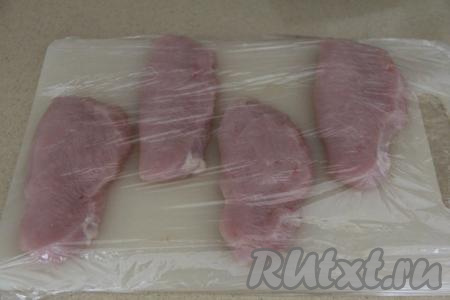 Филе индейки промыть водой, затем немного обсушить и нарезать на порционные кусочки. У меня получилось 4 куска толщиной примерно 1,5 сантиметра. Выложить кусочки индейки на разделочную доску, прикрыть пищевой плёнкой. Отбить филе индейки с двух сторон с помощью кулинарного молоточка.