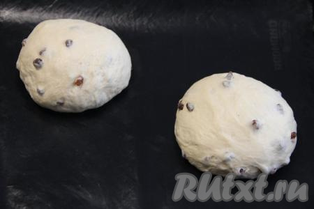 Тесто поднимется и округлится. Обмять тесто, разделить на две части и сформировать два круглых хлеба. Выложить домашний хлеб с изюмом на противень, застеленный ковриком для выпечки (или пергаментом).