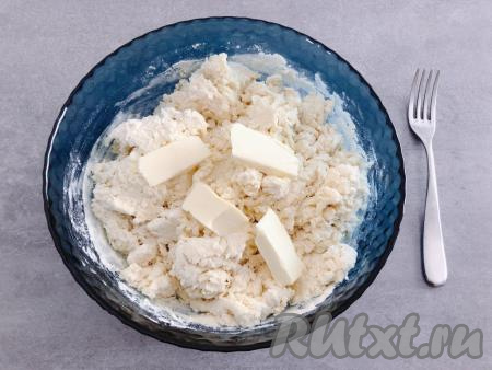 В получившуюся смесь просеиваем часть муки, смешанной с разрыхлителем, тщательно перемешиваем вилкой. Добавляем частями оставшуюся муку, каждый раз тщательно вмешивая её вилкой в творожное тесто. Тесто должно получиться густым, комковатым и тугим. Добавляем в него кусочки мягкого сливочного масла и далее вымешиваем тесто руками, тщательно вмешивая масло и собирая тесто в ком. Творог и молоко могут быть разной жирности, мука тоже бывает разной, поэтому если вдруг тесто не будет собираться в ком, влейте в него 1 столовую ложку молока.