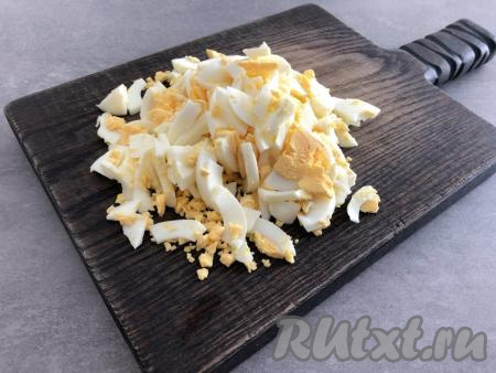 Сварить 4 яйца вкрутую (то есть варить в течение 10 минут с момента закипания), затем остудить их, очистить от скорлупы и нарезать некрупно.