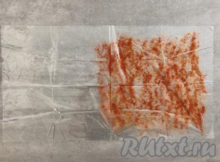 Готовить колбасу будем с использованием рукава для запекания. Отрезаем рукав длиной 70 сантиметров (у меня получился прямоугольник длиной 70 сантиметров и шириной 40 сантиметров). Половину получившегося прямоугольника посыпаем молотой паприкой, немного отступив от краёв (как на фото).