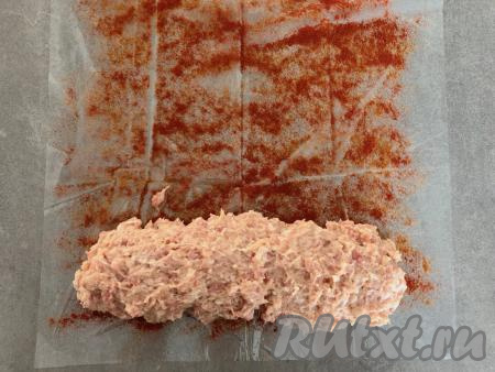 Затем на узкую сторону, посыпанную паприкой, выкладываем полоской фарш, как на фото, немного отступив от края с каждой стороны.