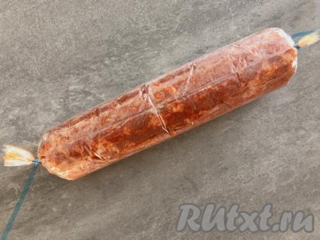 Сворачиваем рукав, начиная со стороны с фаршем, в виде колбаски. Затем края рукава с двух сторон скрепляем специальным зажимом для рукава (или можно туго завязать плотной нитью). Получится заготовка домашней колбасы из фарша, завёрнутая в рукав.