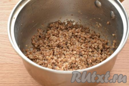 Прежде всего сварим гречневую кашу, для этого нужно промыть гречку водой, убирая, если они есть, испорченные зёрнышки, затем переложить в кастрюлю, залить 200 миллилитрами воды комнатной температуры, поставить на огонь, а после закипания подсолить и варить на небольшом огне 15 минут. Для приготовления гречаников нам понадобится примерно 200 грамм остывшей варёной гречки. Кстати, для этого блюда можно взять&nbsp;гречневую кашу, сваренную накануне (например, к ужину).