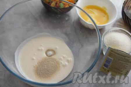 Ряженку влить в глубокую миску, всыпать сухие дрожжи и ванильный сахар.