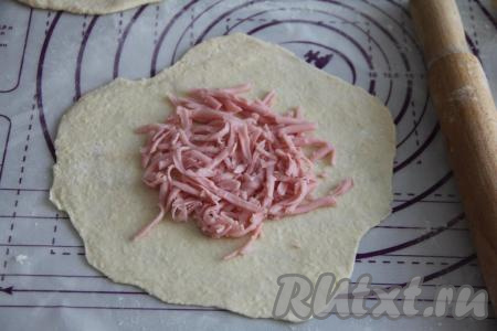 Ветчину натереть на крупной тёрке. Сырное тесто разделить на 8 частей (мы будем готовить 8 лепёшек). Натёртую ветчину зрительно разделить на 8 равных частей (по количеству лепёшек). Каждую часть теста на присыпанной мукой поверхности раскатать скалкой в достаточно тонкий круг, в центр выложить часть ветчины.