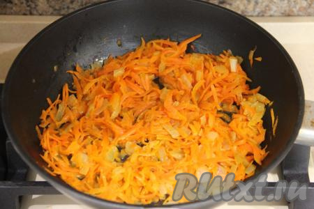 К луку, обжарившемуся до золотистости, выложить натёртую на крупной тёрке морковку, перемешать овощи и обжаривать их вместе, иногда перемешивая, до мягкости моркови (минут 7-8). Затем убрать обжаренные овощи с огня и дать им остыть.